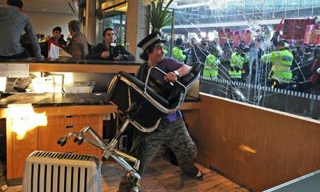Student protesters smash windows as they clash with police after entering Tory HQ at Millbank Tower, London. 
