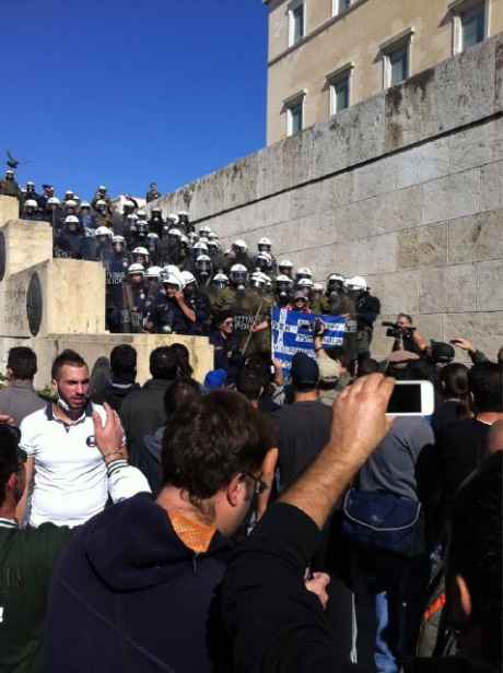 Angry greeks at steps of parliament, which is filled with riot squad